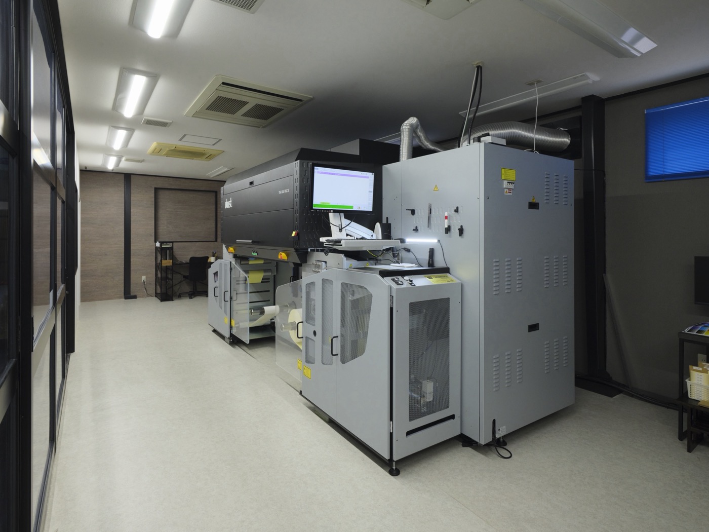 デジタル印刷機 Durst Tau 340 RSC E の全景。型番表示のある本体・制御モニター・ロール原反の巻取部が並ぶ